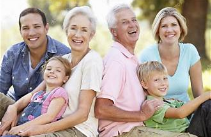 Three generations of a family — grandparents, parents, and grandchildren — smiling together outdoors
